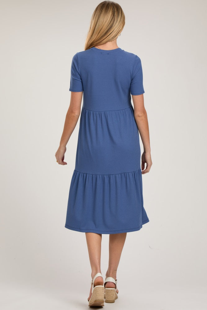 woman wearing a blue short sleeve maternity dress with a tiered skirt detail, showing the back view