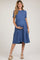 woman wearing a blue short sleeve maternity dress with a tiered hem and holding her baby bump