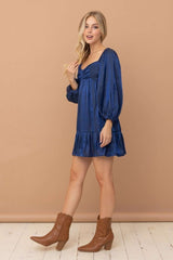 woman wearing a navy blue puff sleeve mini dress with a ruffled hem and brown ankle boots