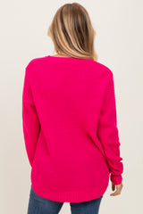 woman wearing a bright pink oversized sweater with a textured knit design and long sleeves, viewed from the back