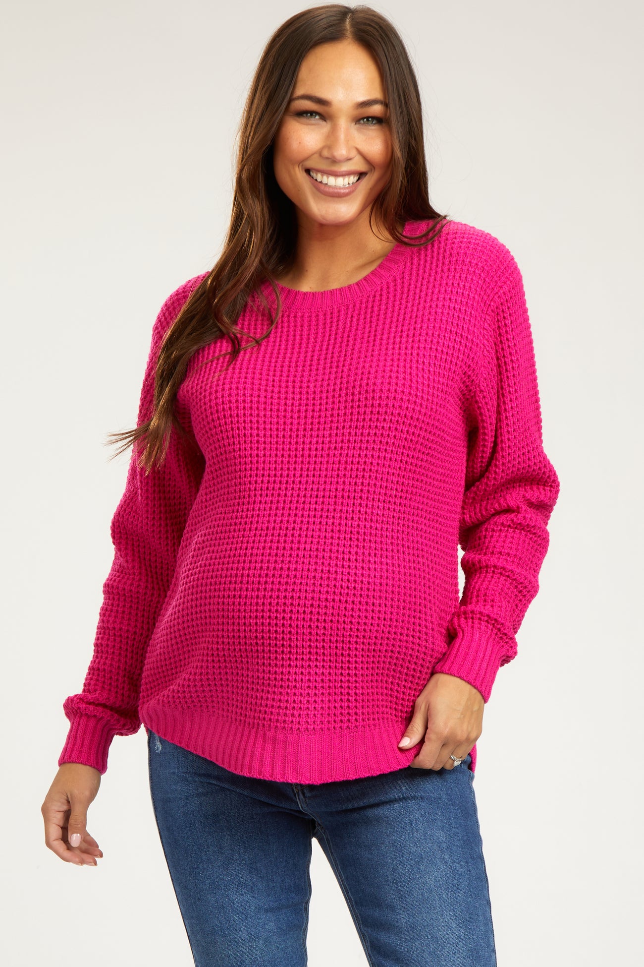 woman wearing a hot pink maternity sweater with a relaxed fit and long sleeves, showing her baby bump