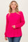 woman wearing a bright pink oversized knitted sweater with a round neckline and side slits, paired with blue jeans