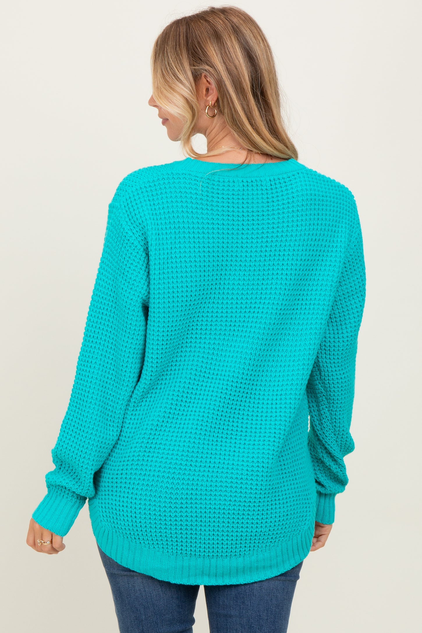 woman wearing a turquoise oversized knit sweater from the back, with long sleeves and a relaxed fit