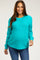 woman wearing a bright turquoise maternity sweater with a loose fit and long sleeves, smiling and showcasing her baby bump