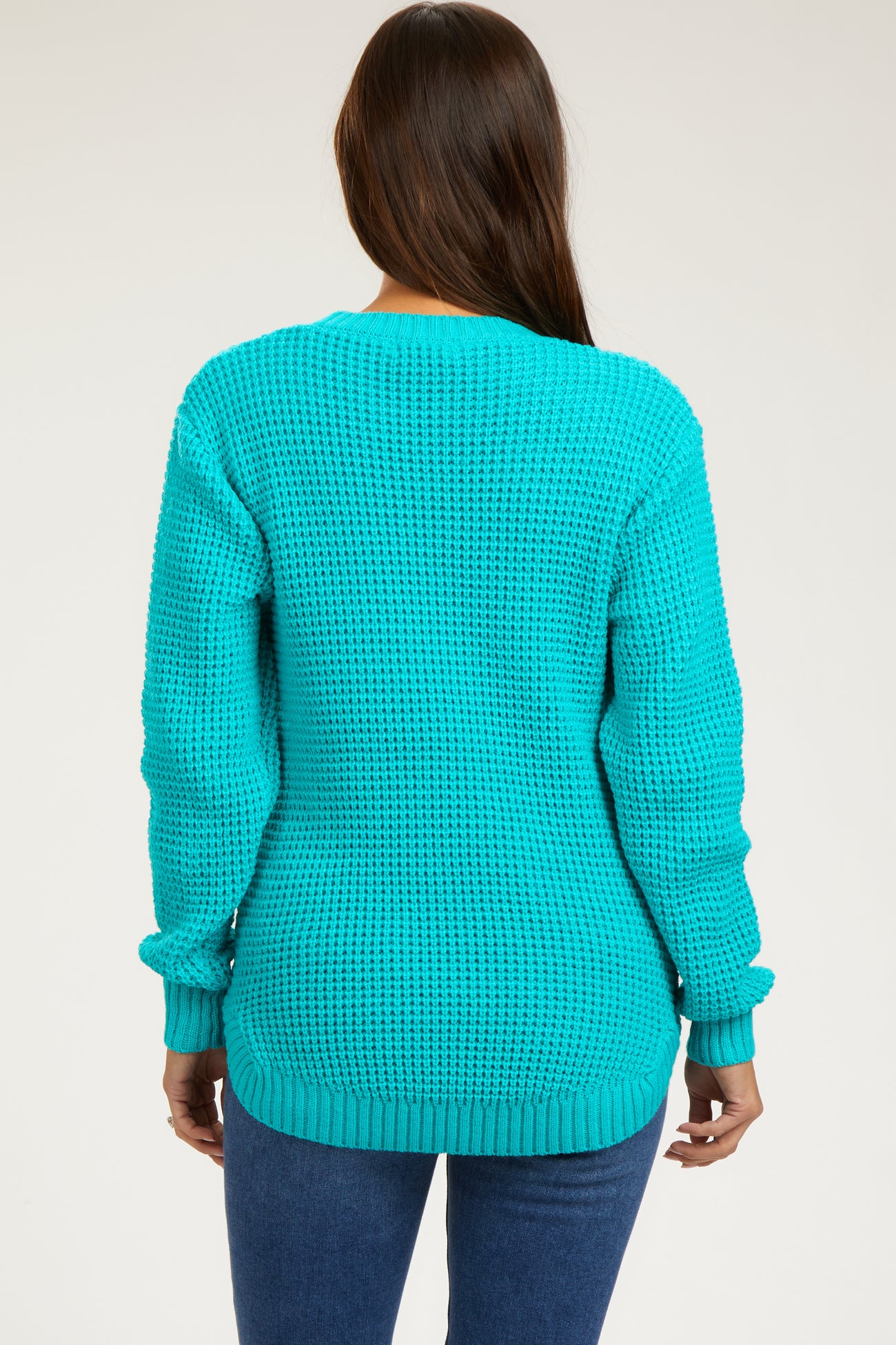 woman wearing a turquoise oversized knitted maternity sweater with long sleeves and back view