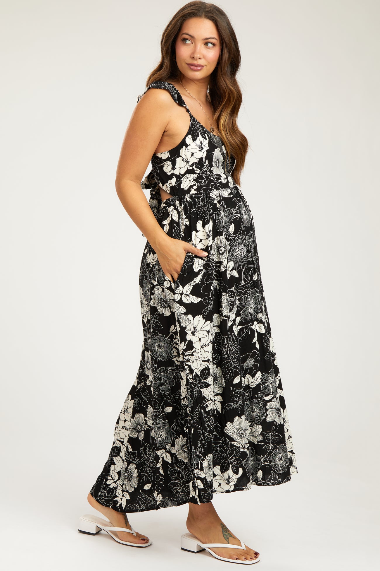 woman wearing a black floral maternity maxi dress with pockets and a baby bump visible