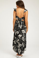 woman wearing a black floral maternity maxi dress with tie back and ruffle sleeves, showing off her baby bump
