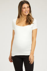 woman wearing a white short sleeve maternity top and showing her baby bump