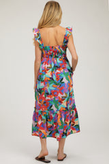 woman wearing a colorful floral print maternity dress with ruffled straps and a tiered hem, showing her back