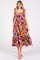 woman wearing a colorful floral midi dress with ruffled straps and pockets, standing against a white background