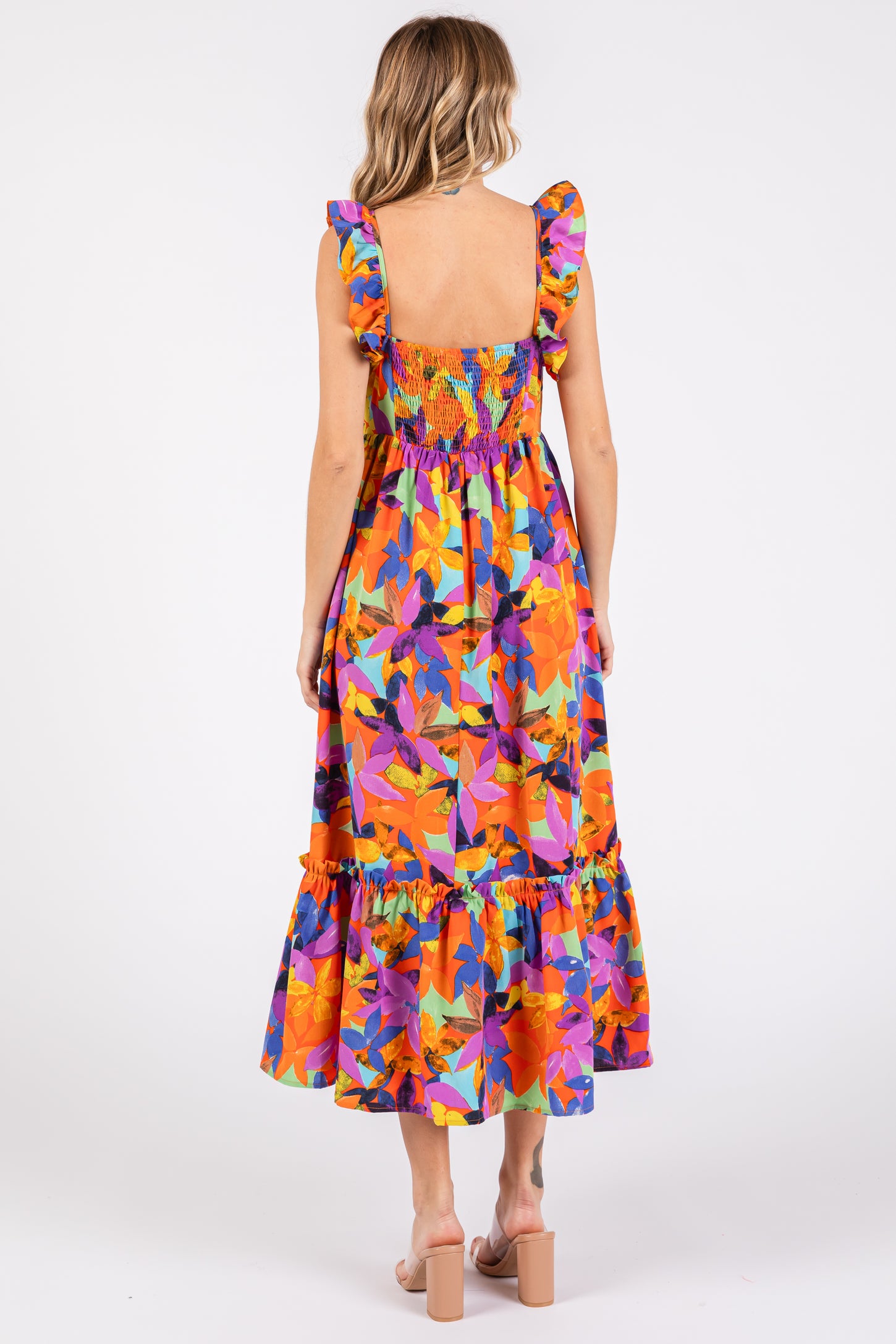 woman wearing a colorful floral maxi dress with ruffled straps and a tiered skirt, shown from the back