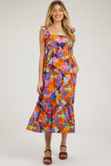 woman wearing a colorful floral maternity dress with ruffle straps and a tiered hem