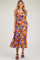 woman wearing a colorful floral maternity dress with ruffle straps and a tiered hem