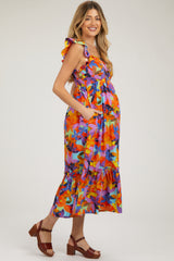woman wearing a colorful floral maternity dress with ruffles and pockets, and showing a baby bump