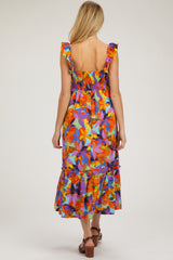 woman wearing a colorful floral printed maternity dress with ruffle straps and a tiered hem, showing her baby bump from the back