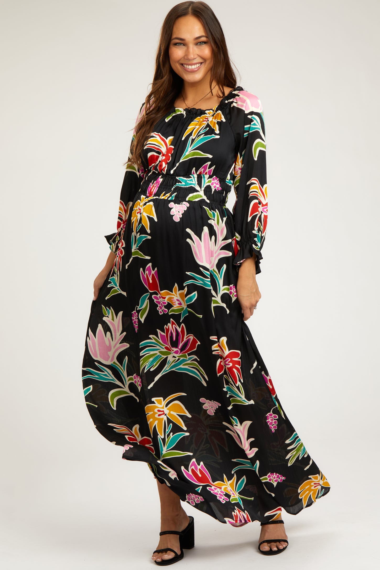 woman wearing a black floral maternity maxi dress with long sleeves and a flowing skirt, showcasing her baby bump