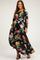 woman wearing a black floral maternity maxi dress with long sleeves and a flowing skirt, showcasing her baby bump