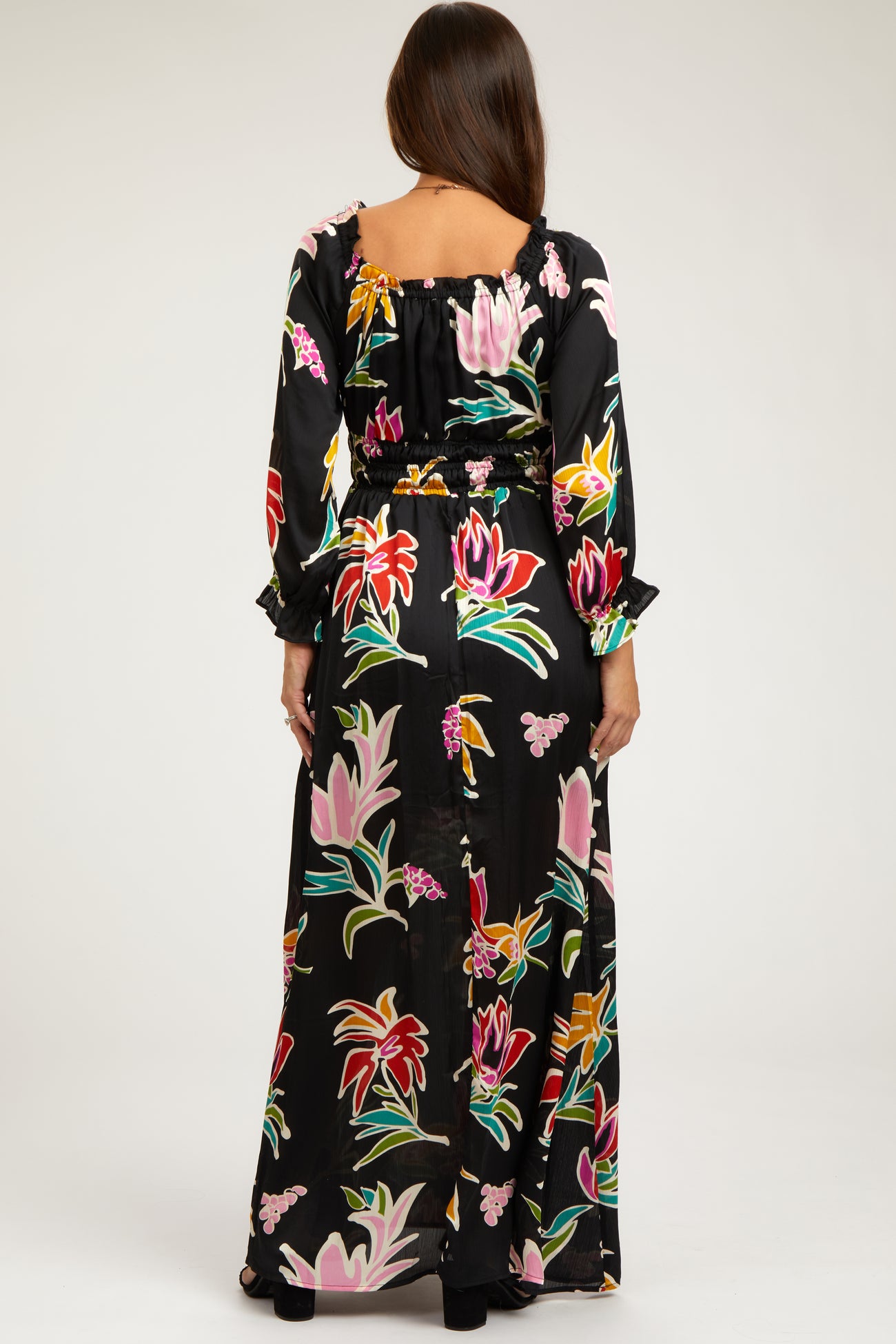 woman wearing a black floral print maternity maxi dress with long sleeves and a cinched waist, showing her baby bump