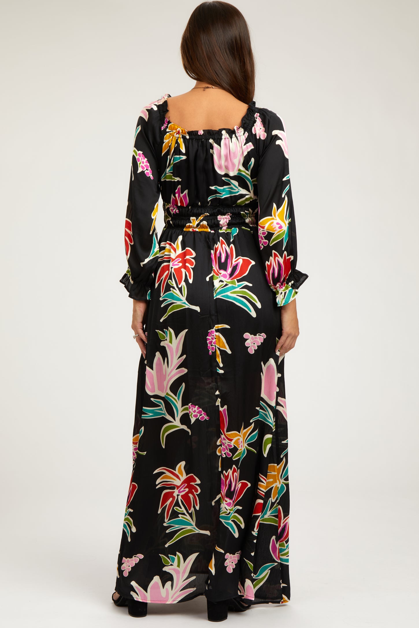 woman wearing a black floral print maternity maxi dress with long sleeves and a cinched waist, showing her baby bump