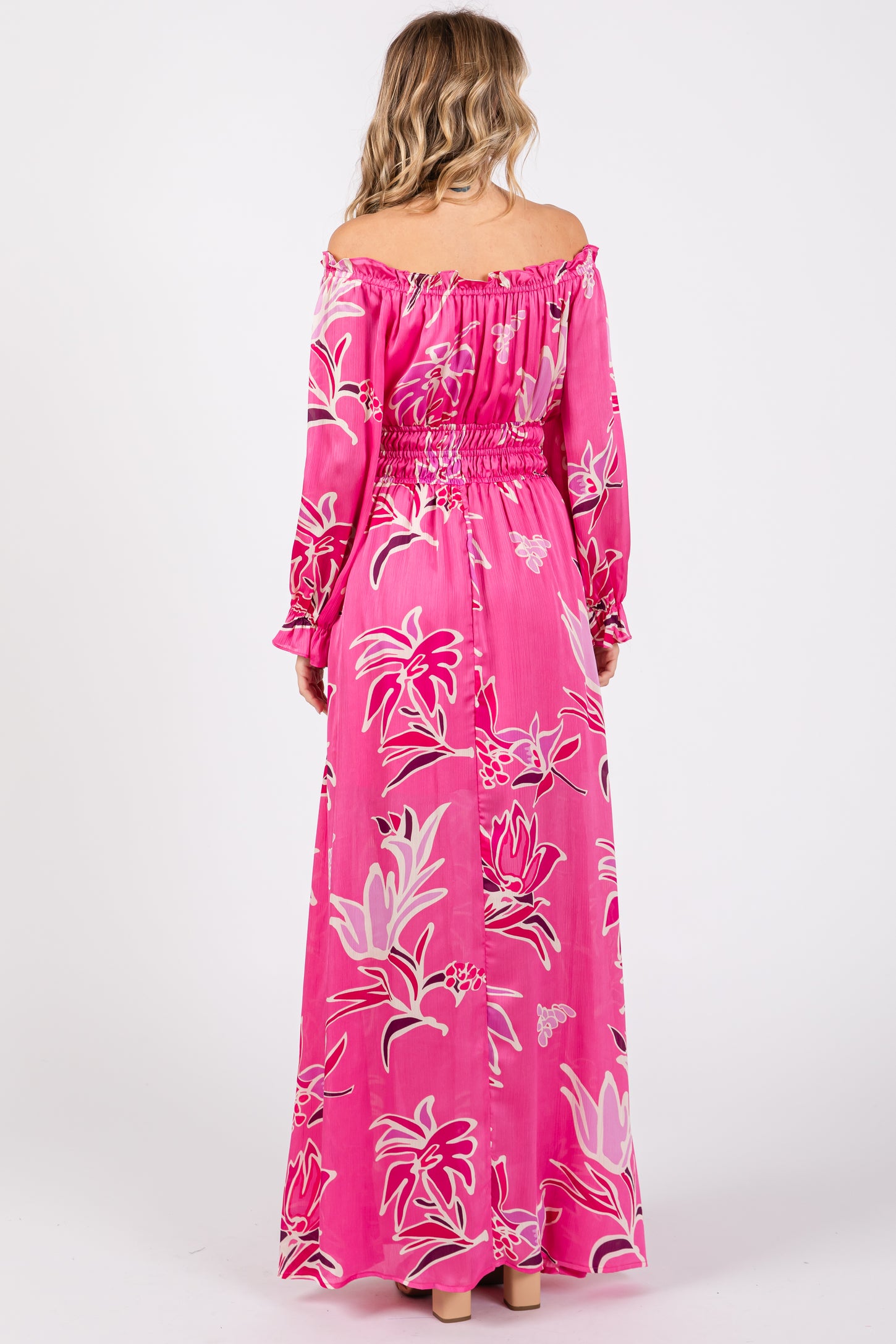 woman wearing a pink off-shoulder maxi dress with floral print and long sleeves, showing the back view