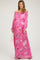 woman wearing a pink off-the-shoulder floral maxi dress with a smocked waist, posing with a handbag