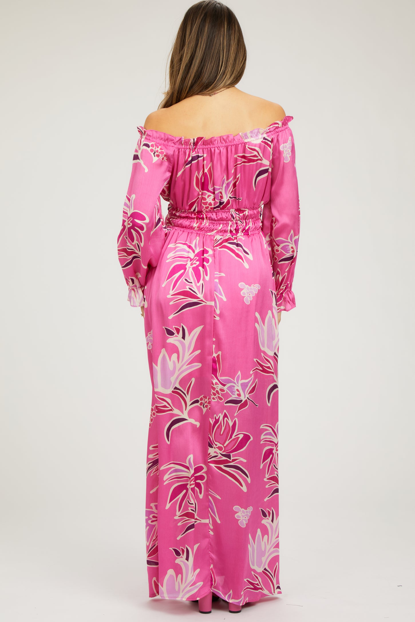 woman wearing a pink floral off-the-shoulder maternity maxi dress with a fitted waist and long sleeves