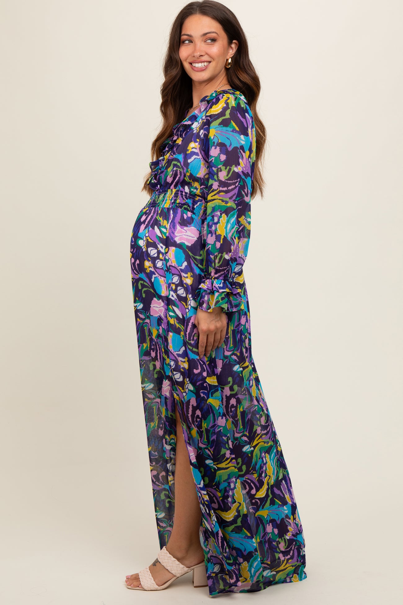 woman wearing a colorful floral maternity maxi dress with long sleeves and a side slit, showing her baby bump