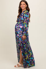 woman wearing a colorful floral maternity maxi dress with long sleeves and a side slit, showing her baby bump