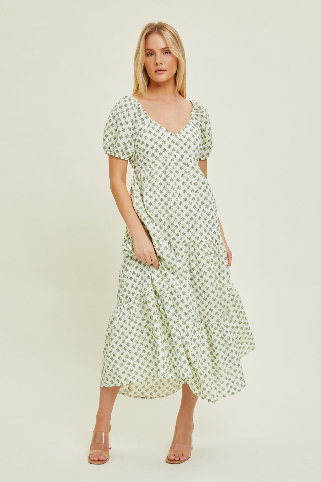 woman wearing a green and white floral print maxi dress with puff sleeves and tiered skirt