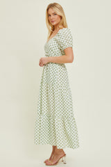 woman wearing a light green floral maxi dress with short sleeves and a tiered skirt