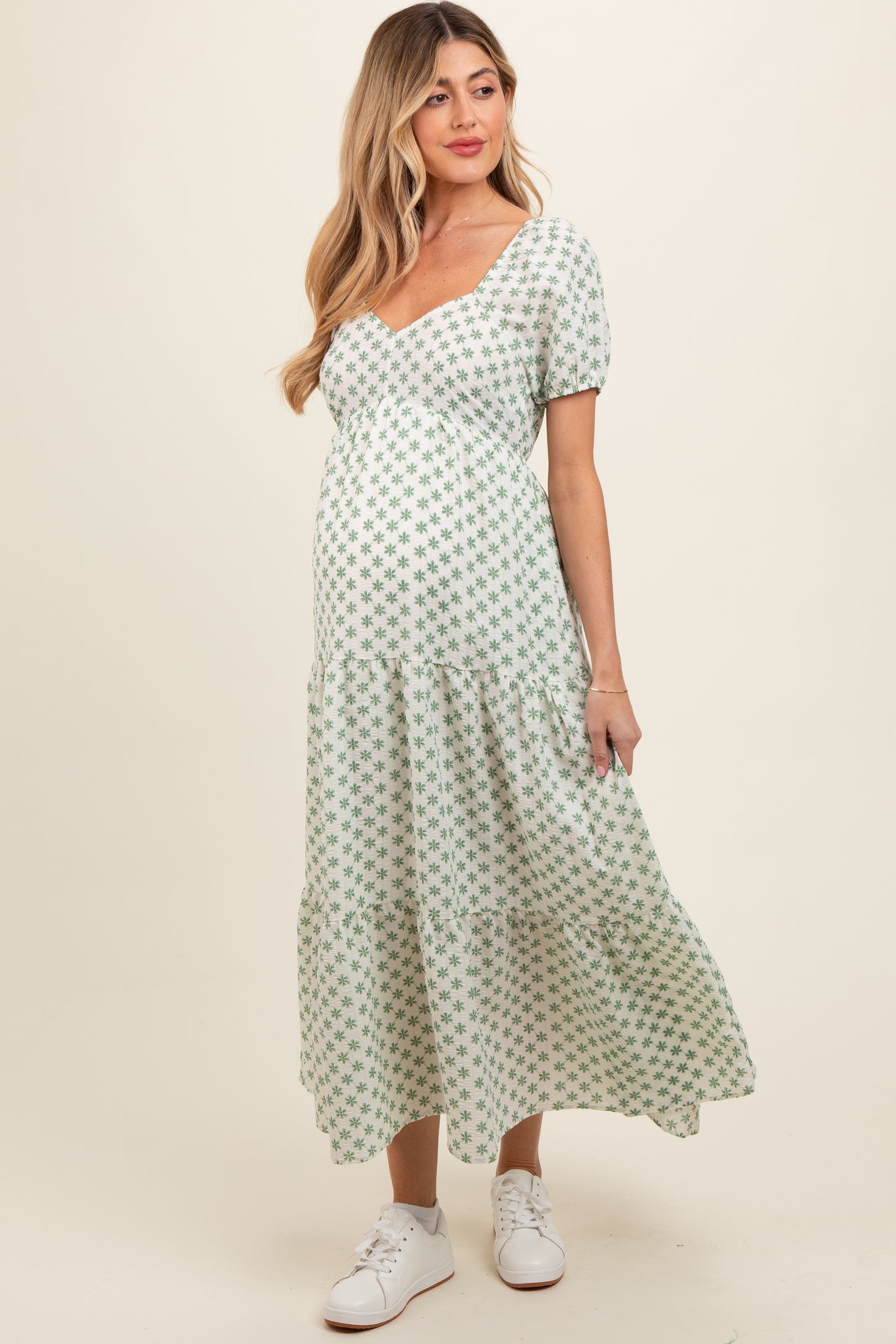 woman wearing a green floral maternity maxi dress with puff sleeves and a baby bump visible