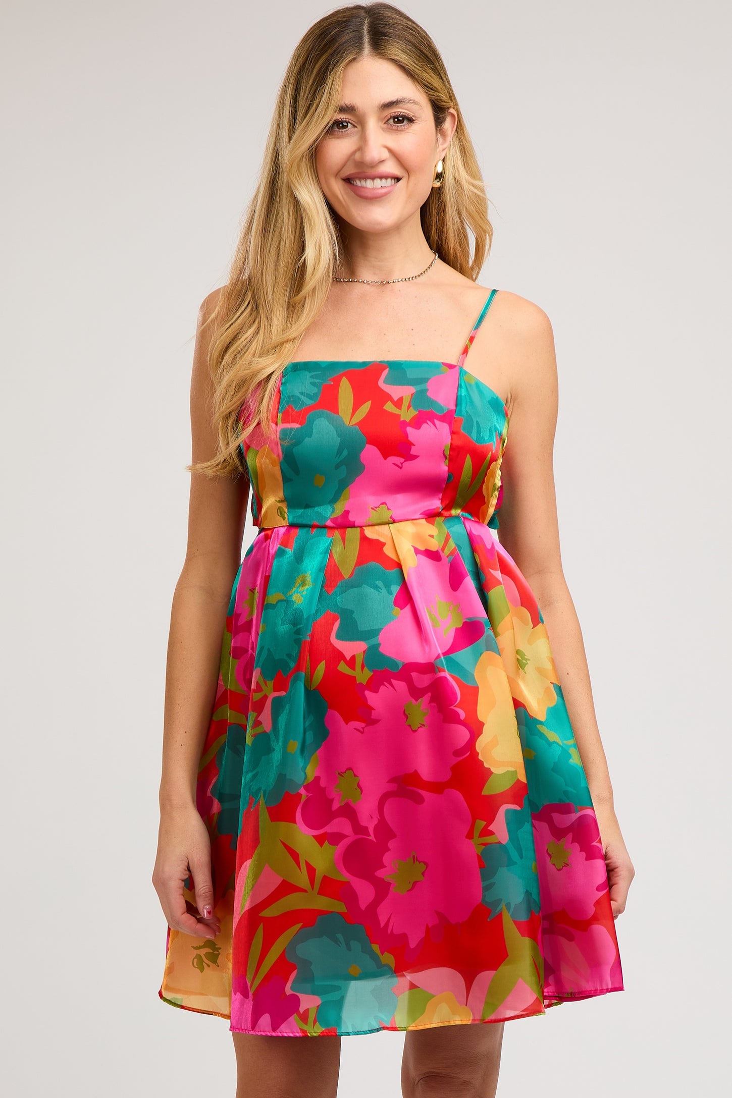 woman wearing a colorful floral maternity dress with a fitted bodice and flowy skirt, showing off her baby bump