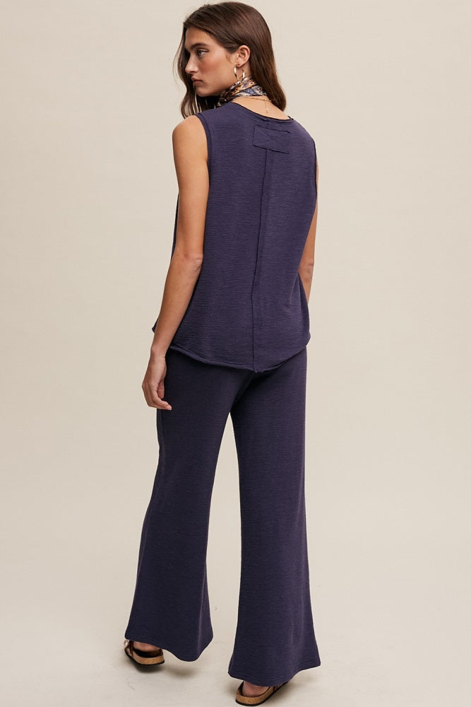 woman wearing a navy blue sleeveless top and matching wide-leg pants, viewed from the back