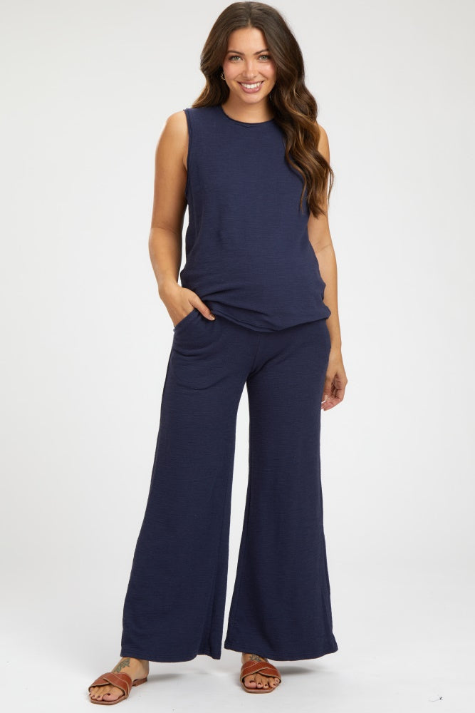 woman wearing a navy blue sleeveless maternity top and matching wide-leg pants, with hands in pockets
