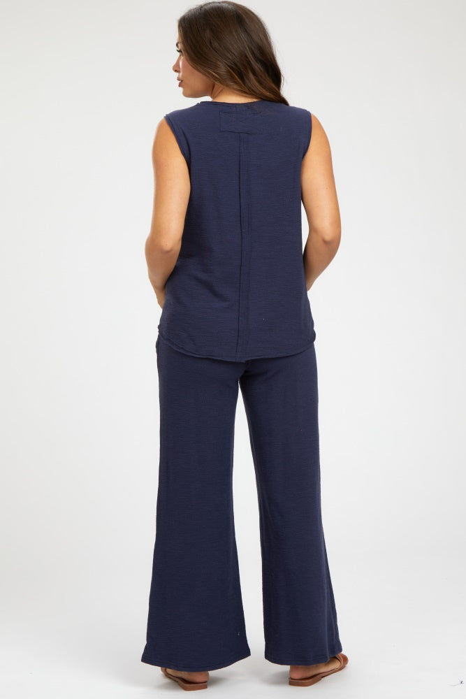 woman wearing a navy blue sleeveless maternity top and matching wide-leg pants, showing a relaxed fit from the back