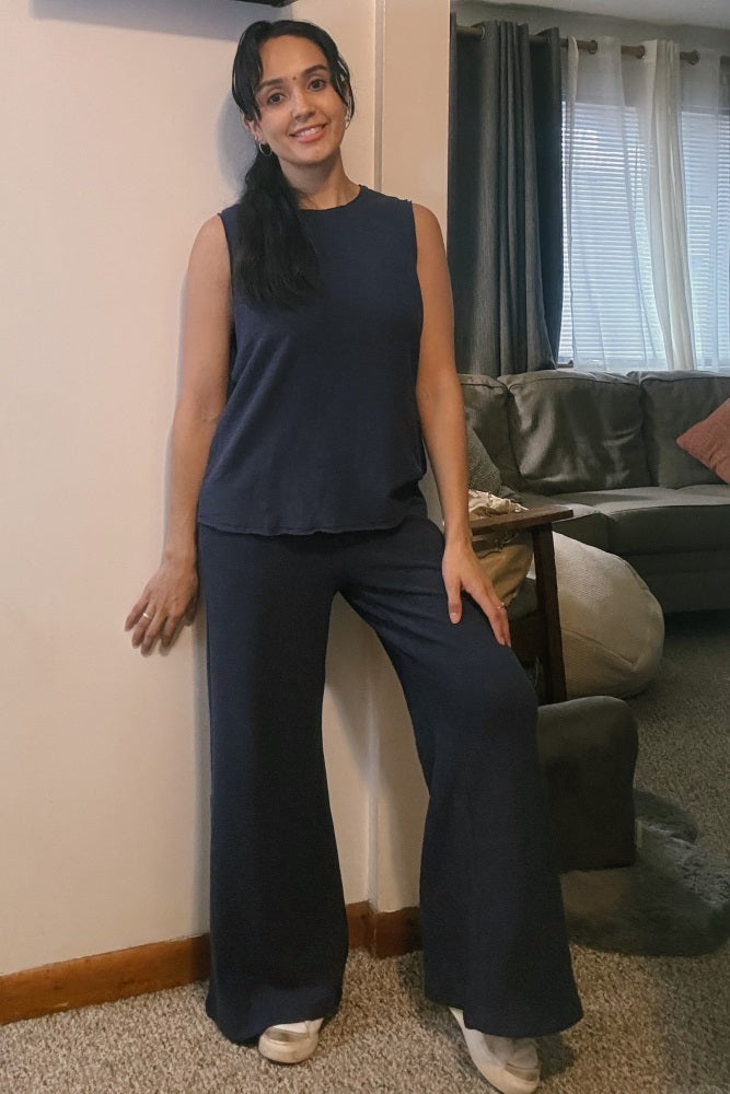 woman wearing a dark navy sleeveless top and matching wide-leg pants, standing in a living room