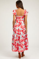 woman wearing a floral maternity maxi dress with ruffled sleeves and a tiered hem, showing her back