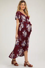 woman wearing a burgundy floral maternity wrap dress with short sleeves and a tied waist, showing her baby bump