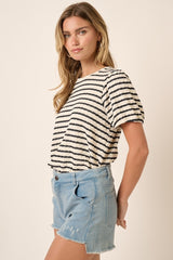woman wearing a cream and navy striped short sleeve top with a relaxed fit and light blue denim cut-off shorts