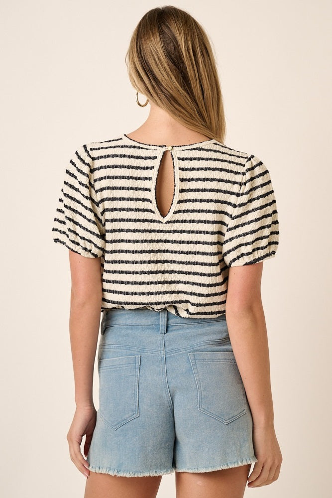 woman wearing a striped short sleeve top with a keyhole back and light blue denim shorts
