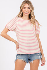 woman wearing a pink and white striped short sleeve top with puff sleeves and distressed denim shorts