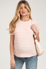 woman wearing a pink and white striped maternity top with short sleeves and holding a cream handbag