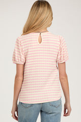 woman wearing a pink and white striped maternity top with short puff sleeves and a keyhole back detail