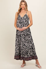 woman wearing a black and white floral maternity maxi dress with a colorful hem and holding her baby bump