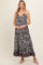 woman wearing a black and white floral maternity maxi dress with a colorful hem and holding her baby bump