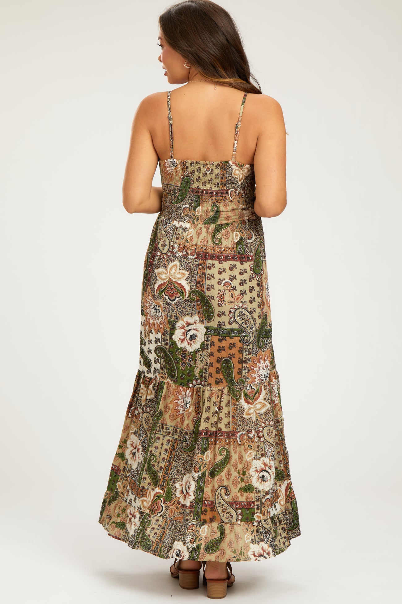 woman wearing a patterned maxi dress with spaghetti straps and a tiered hem, showcasing the back view