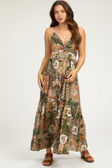 woman wearing a floral print maternity maxi dress with a halter neckline and adjustable straps, showing her baby bump
