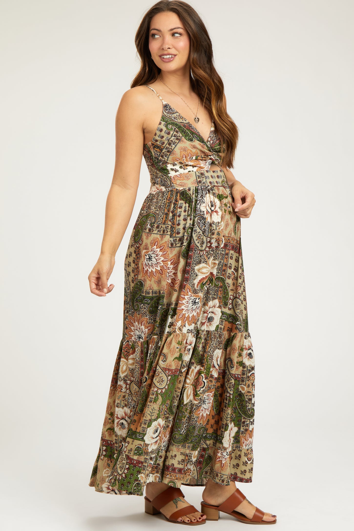woman wearing a flowy floral print maternity maxi dress with a wrap style and adjustable straps, displaying her baby bump