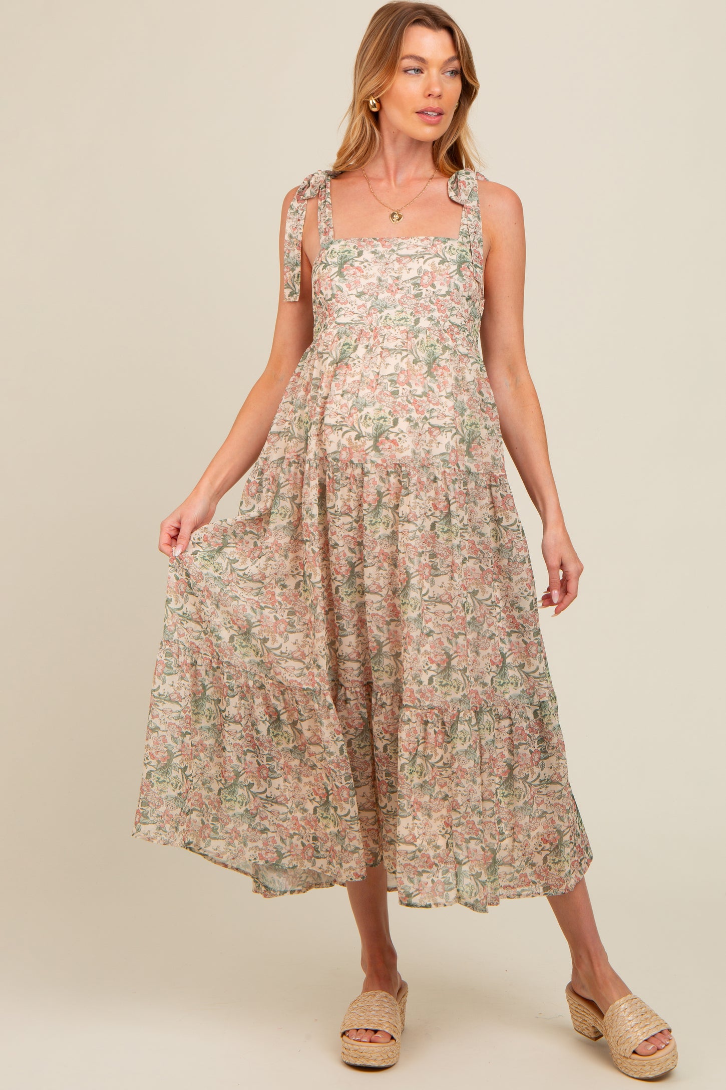 woman wearing a floral maternity maxi dress with tie straps and a flowing skirt, showcasing her baby bump