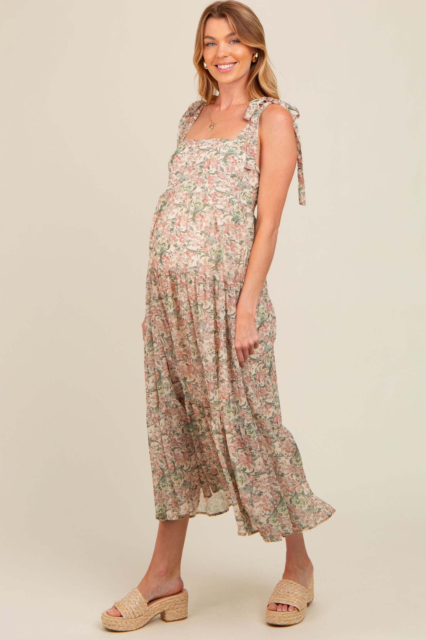 woman wearing a floral maternity maxi dress with tie straps and a visible baby bump